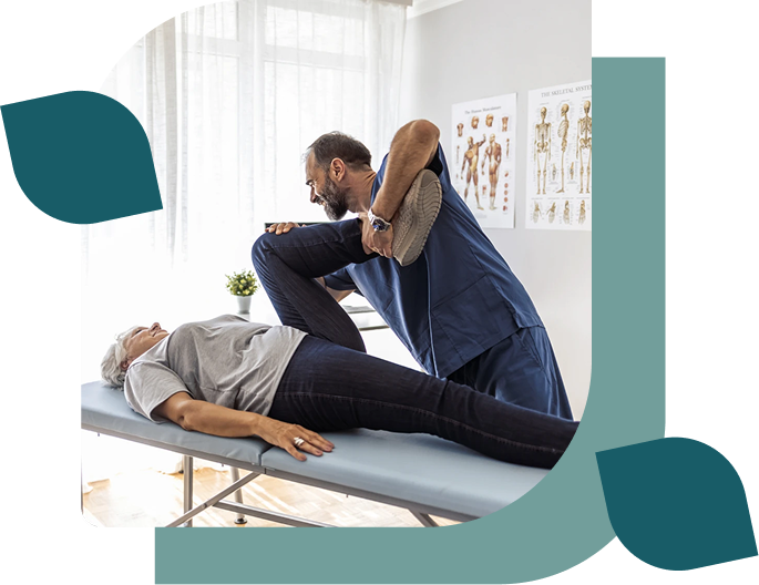 Therapist stretching patient's leg on table.